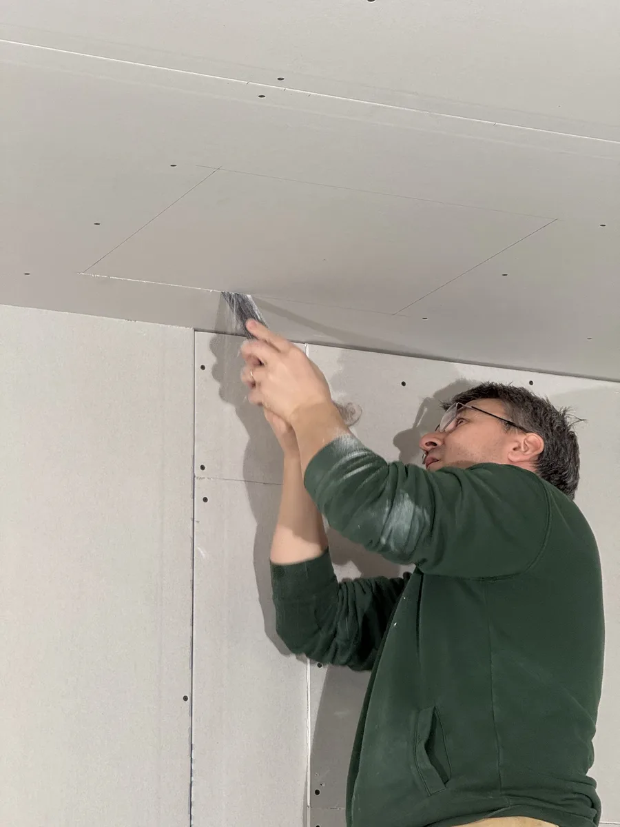 Cartongessista al lavoro con la normale attrezzatura del secco